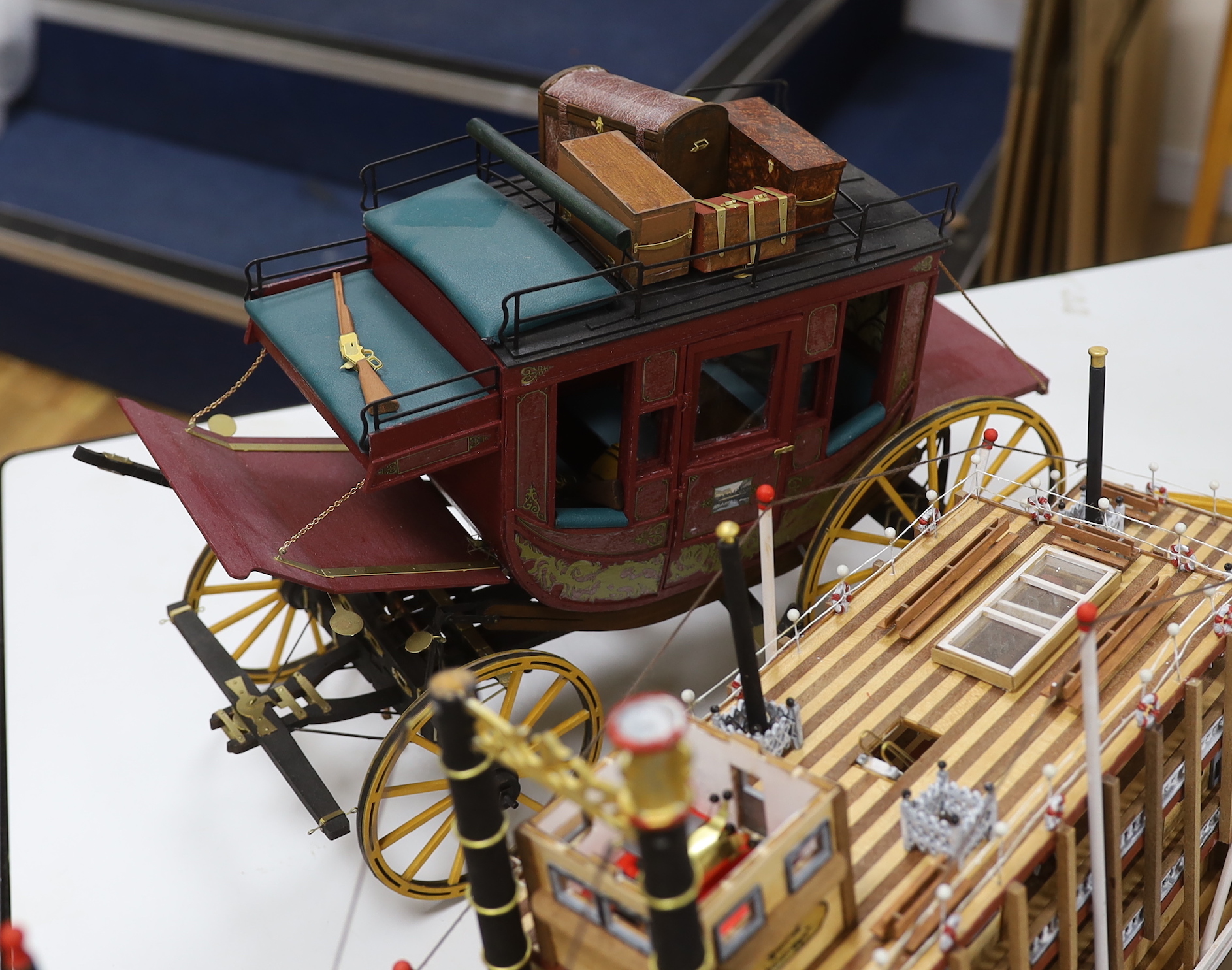 Two scratch built wooden model boats; a Mississippi style paddle steamer and a steam tug, together with a U.S. Western style coach plus a pocket watch and stand in the form of a long case clock, tug length 81cm